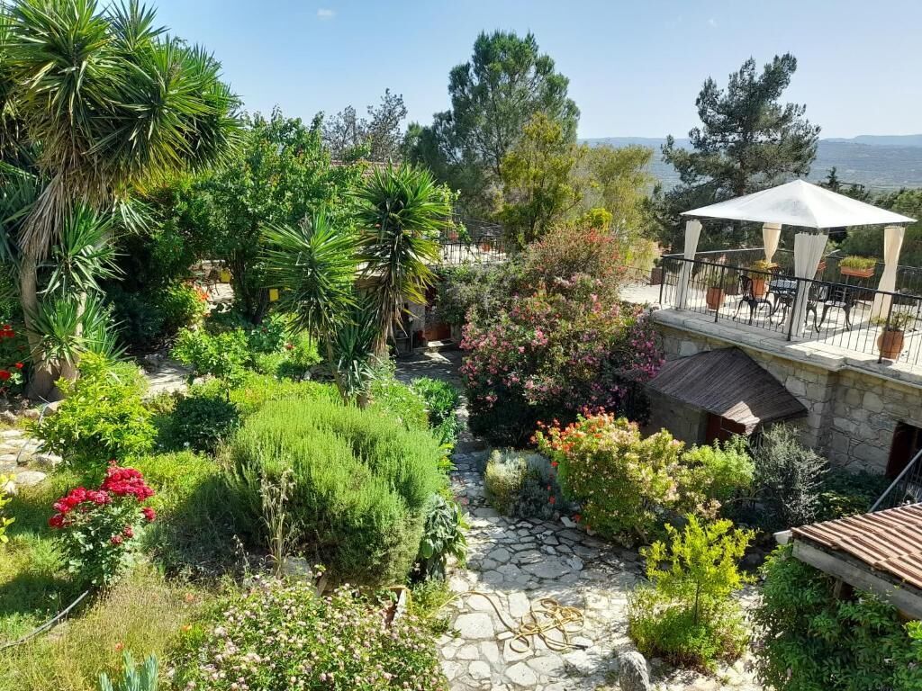 A garden with a stone pathway, a gazebo, and a view of the sea.