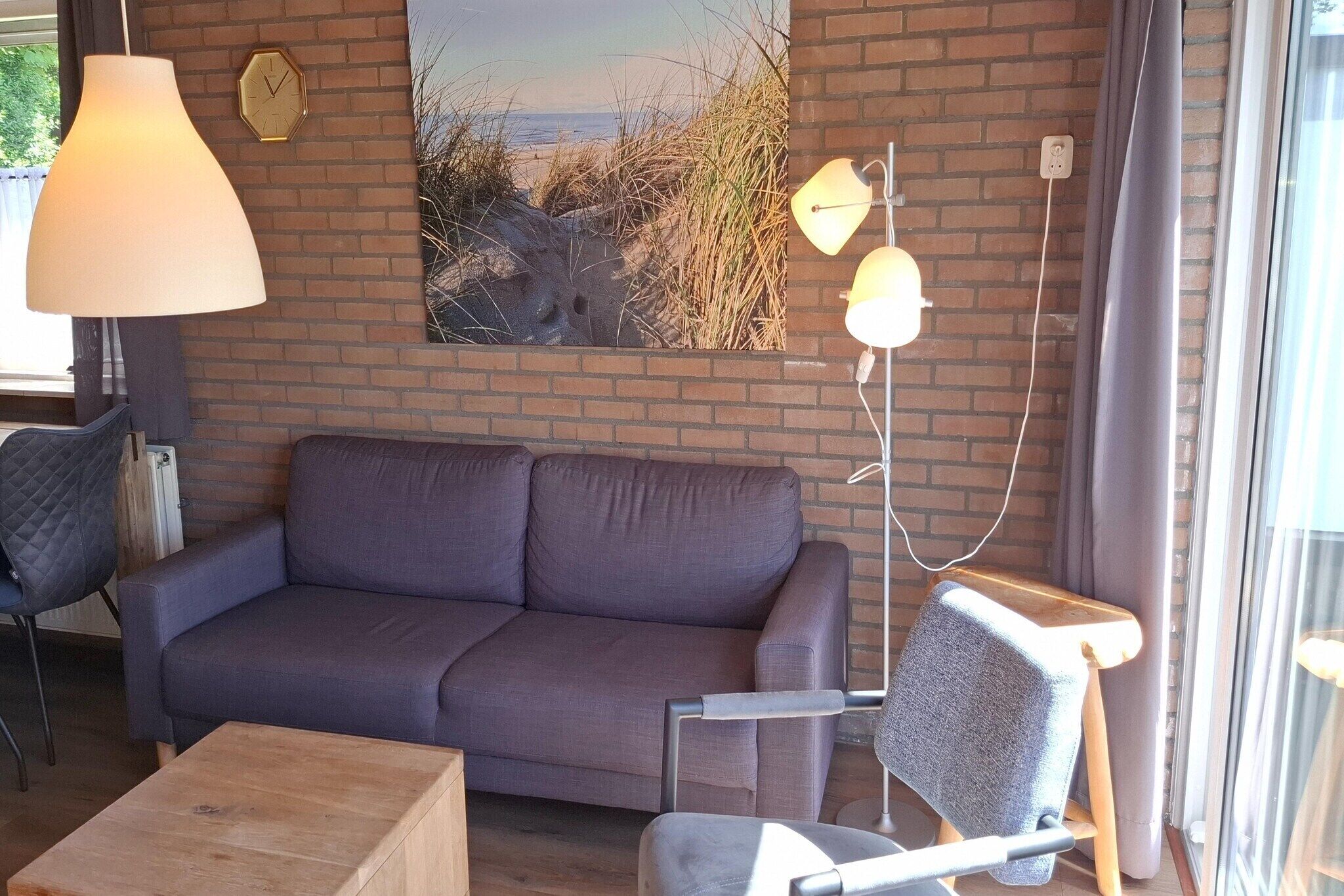 Una habitación con un sofá, una silla, una lámpara y un cuadro en la pared.
