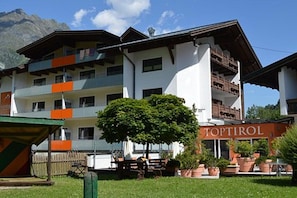 A multi-story hotel with balconies, a sign reading 'TOPTIROL,' and a tree in the foreground. - Holiday apartment with wellness area (Längenfeld)