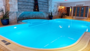Une piscine intérieure avec un mur en pierre et une pancarte indiquant « TÉPIDARIUM ».