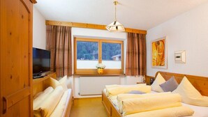 Une chambre d’hôtel avec un lit, une télévision, une fenêtre avec des rideaux et un tableau au mur.