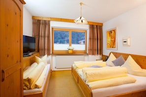 A hotel room with a bed, a television, a window with curtains, and a painting on the wall. - Holiday apartment with wellness area (Längenfeld)