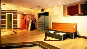 Un hall d’hôtel comprenant un comptoir d’accueil, un escalier et un espace détente avec un panneau de tête en bois.