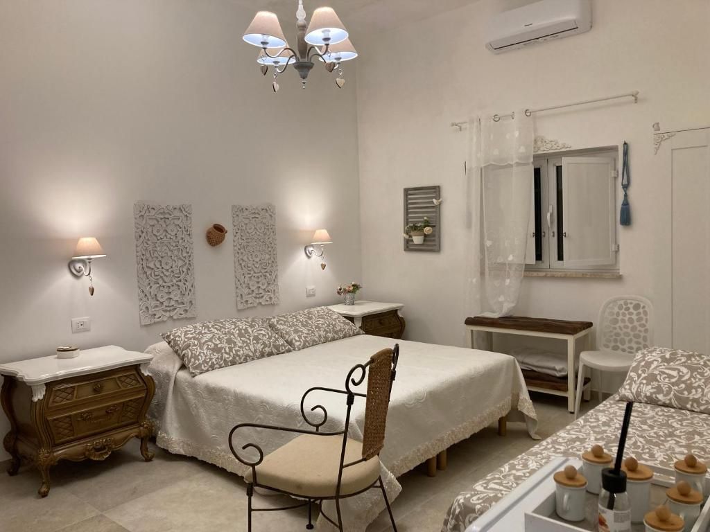 A bedroom with a bed, bedside tables, a chair, a desk, and a window with curtains.