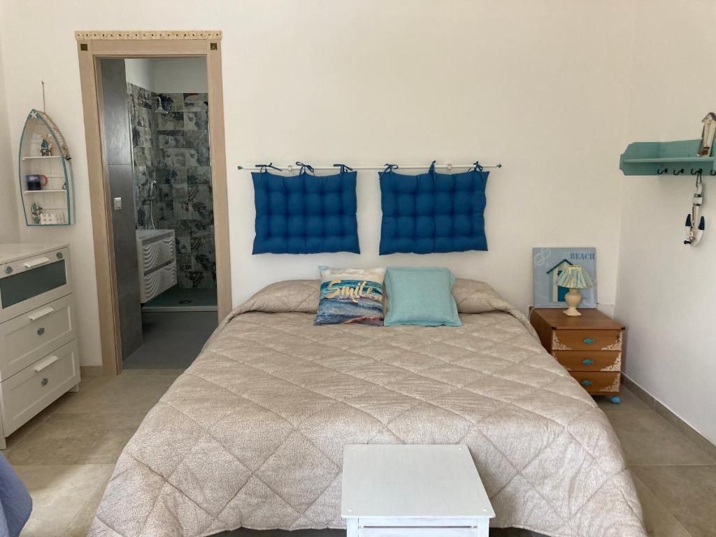 Un dormitorio con cama, mesita de noche, cómoda, estante con lámpara y zona de ducha.