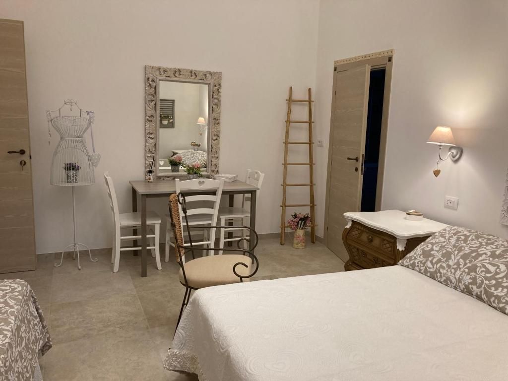 A bedroom with a bed, a desk, a chair, a dresser, and a mirror.