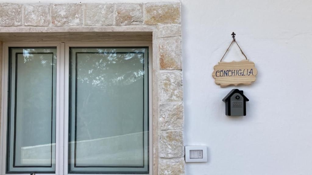 A stone wall with a wooden sign reading 'CONCHIGLIA' and a birdhouse.