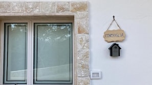 Un muro de piedra con un letrero de madera que dice 'CONCHIGLIA' y un comedero para pájaros.