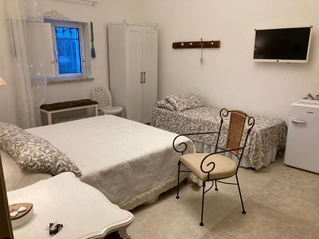 Une chambre à coucher comprenant un lit, une chaise, un bureau, une armoire, un téléviseur et une petite table sur laquelle se trouvent un bol et des pierres.