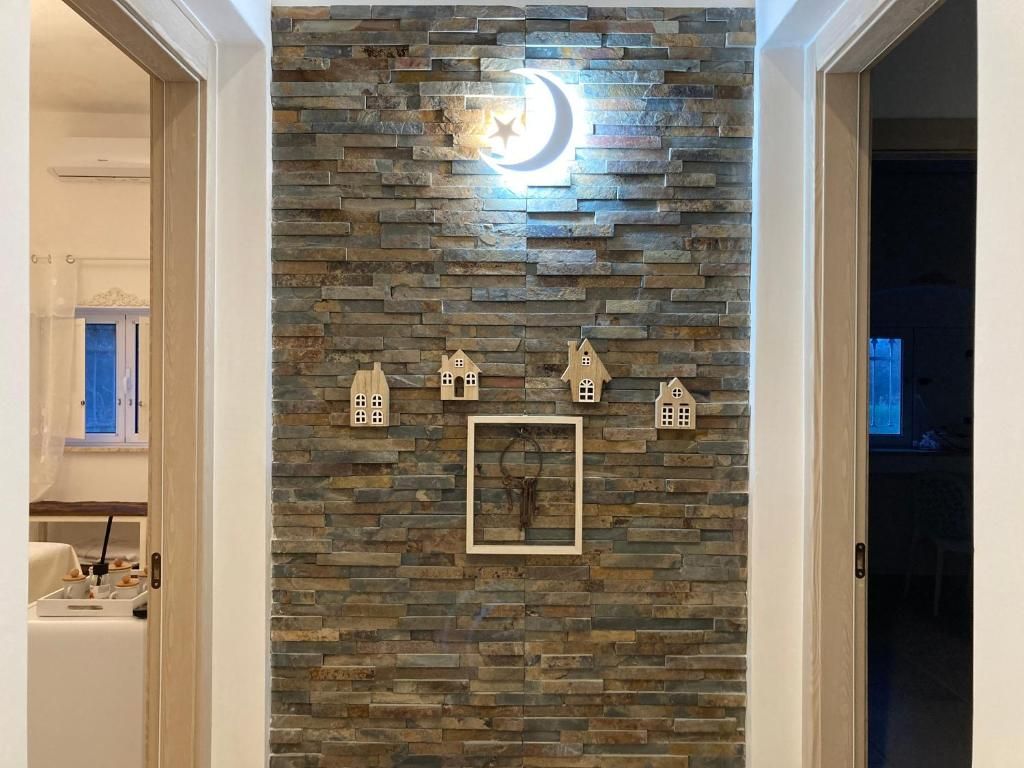Un muro de piedra con una decoración de luna creciente y estrella, un cuadro enmarcado y pequeños adornos con forma de casa.