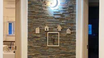 Un muro de piedra con una decoración de luna creciente y estrella, un cuadro enmarcado y pequeños adornos con forma de casa.