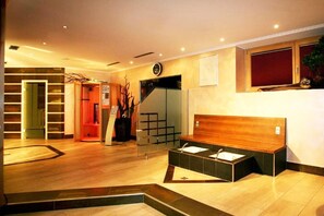 A hotel lobby with a reception desk, a staircase, and a seating area with a wooden headboard. - Holiday apartment with wellness area (Längenfeld)