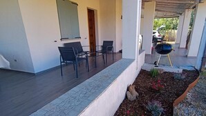 A covered patio area with outdoor seating, a barbecue grill, and a garden bed with plants. - Villa 'Casa Bougainvillea' with Mountain View, Wi-Fi and Air Conditioning (Lu Muntiggiu di La Petra I)