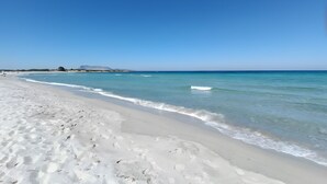 A beach with clear blue water, white sand, and a distant mountain. - Villa 'Casa Bougainvillea' with Mountain View, Wi-Fi and Air Conditioning (Lu Muntiggiu di La Petra I)