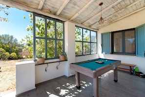 Una mesa de billar en una sala con ventanas amplias y vistas al exterior.