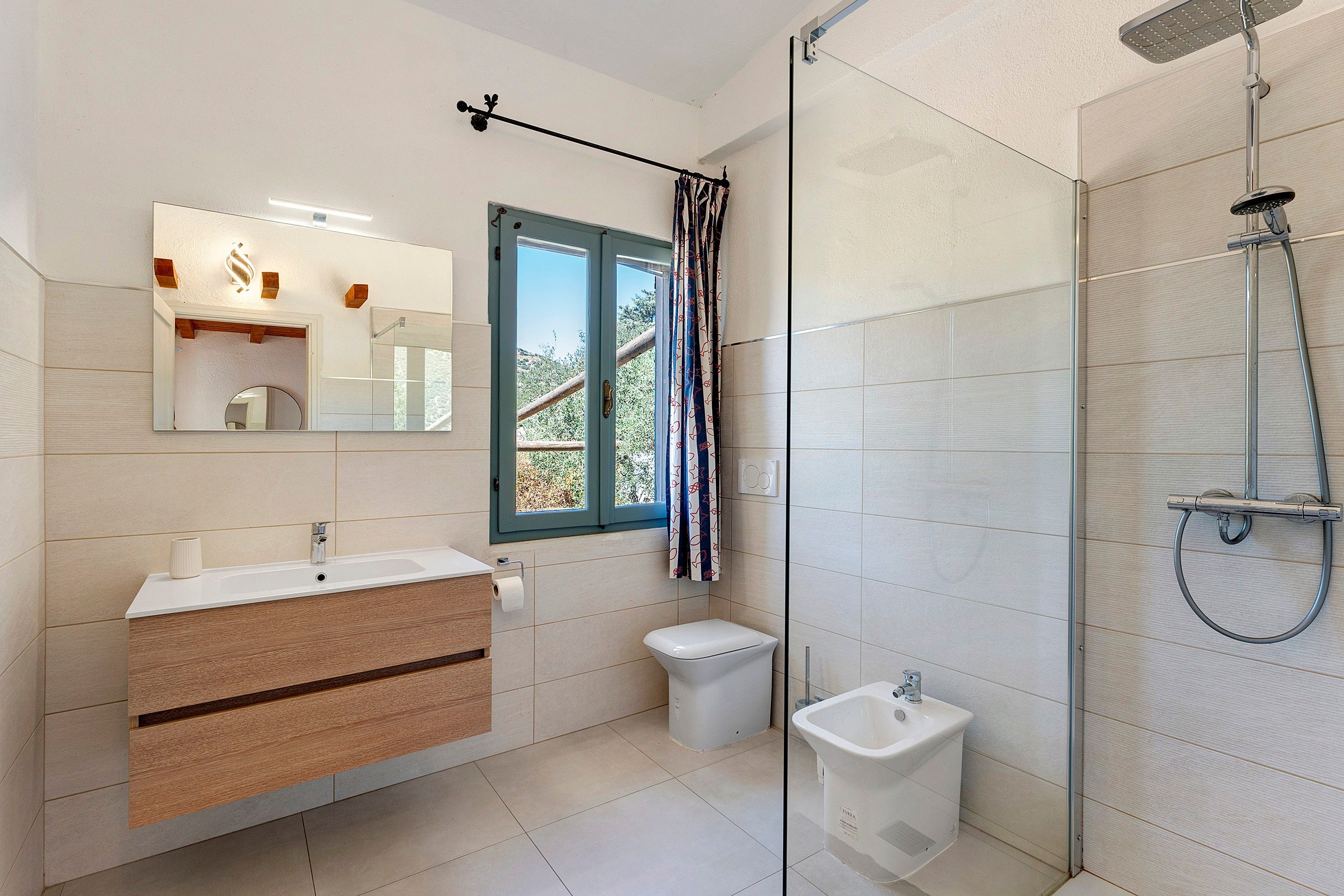 Une salle de bain moderne équipée d’une douche, de toilettes, d’un bidet et d’un meuble-lavabo avec un miroir et un évier.