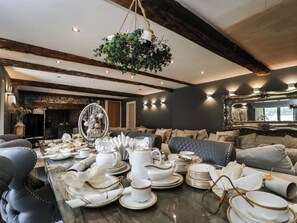 A dining area with a marble table set for a meal, a fireplace, and a chandelier. - Llanfarach Farmhouse (Pontyclun)