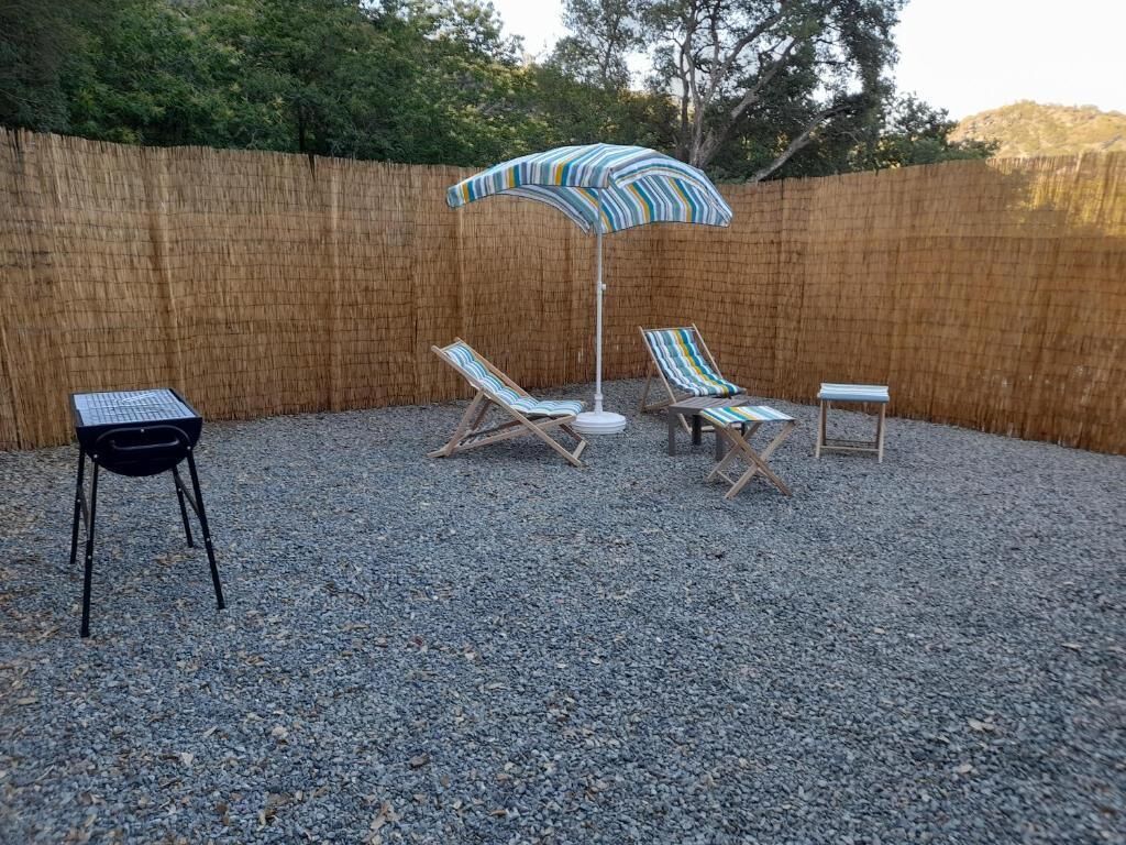 Ein Garten mit Bambuszaun, Kiesgrund und einem gestreiften Sonnenschirm.
