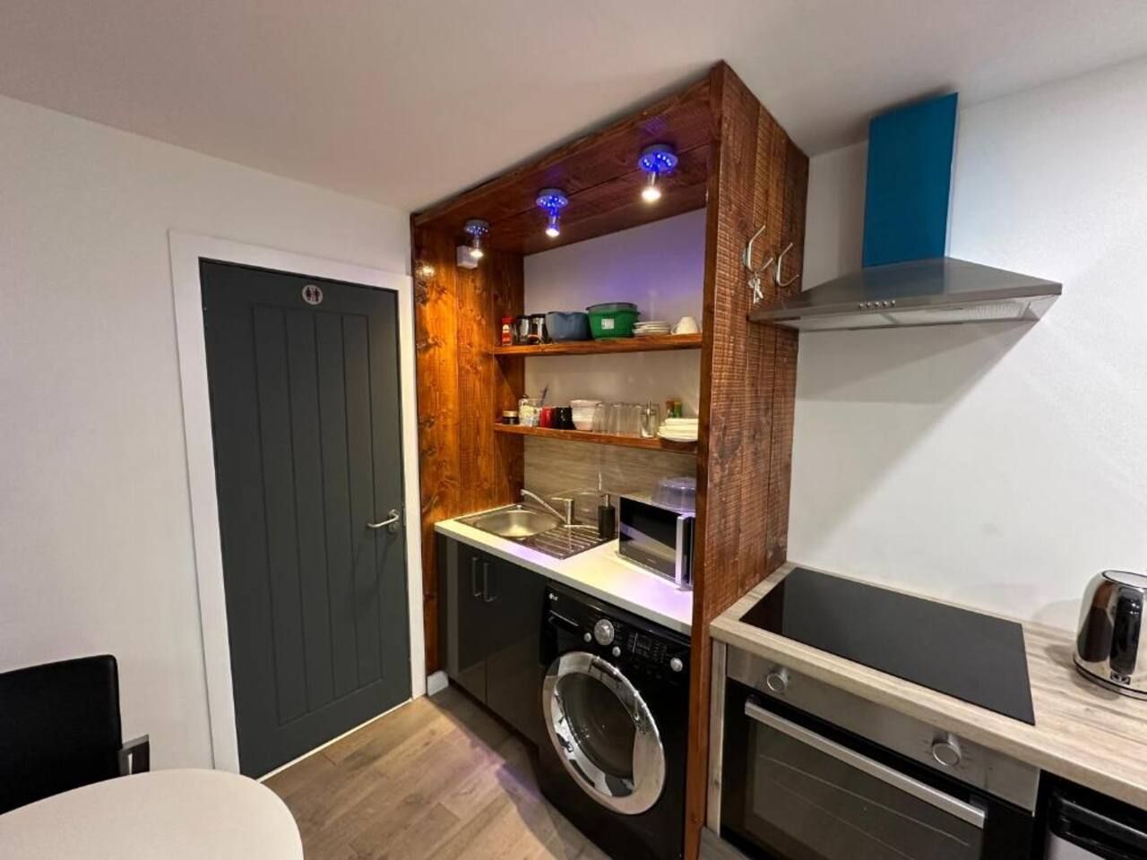 A compact kitchen with a washing machine, a microwave, and a toaster.