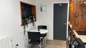 Una cucina compatta con tavolo, sedie, orologio e una porta.