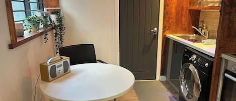 A compact kitchen with a washing machine, a sink, and a dining area with a table and chairs.