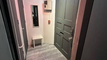 Un pasillo estrecho con un banco, una puerta y un equipo de aire acondicionado instalado en la pared.