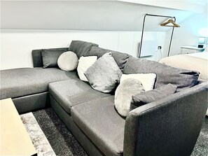 A modern living room with a grey sectional sofa, multiple cushions, a black floor lamp, and a white wall. - Cottage near City Canal, OpenSpace on 2 levels, 5pp, Parking (South Yorkshire)