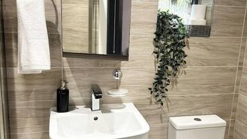 Ein Badezimmer mit weißem Waschbecken, Toilette, Spiegel und Handtuchhalter.
