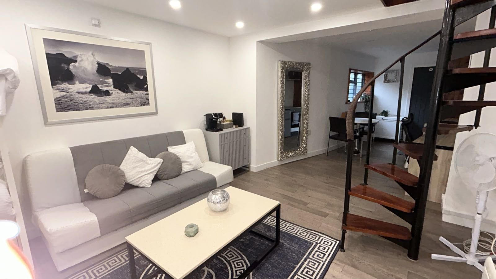 Uma sala de estar moderna com um sofá, uma mesa de centro e uma moldura com um quadro na parede.