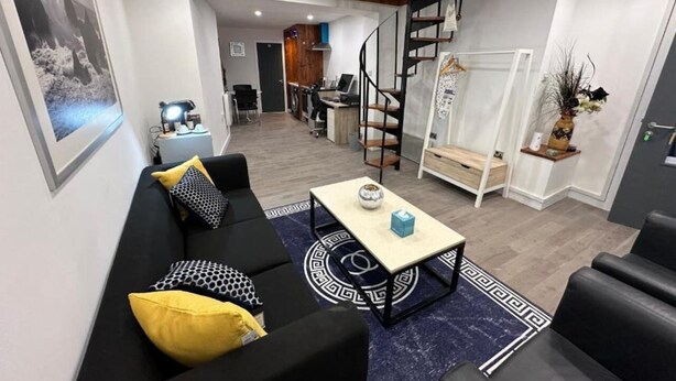Un soggiorno moderno con divano, tavolino e una scala che conduce a una zona cucina.
