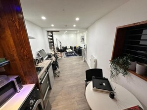 A modern kitchen with a dining area, a staircase leading to another level, and a view of the living room.