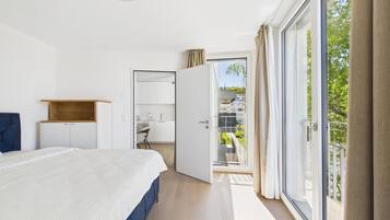 Ein Schlafzimmer mit Bett, Schreibtisch, Kleiderschrank und einem Balkon mit Blick.