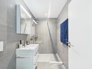 Ein modernes Badezimmer mit Dusche, Waschbecken und Spiegel.
