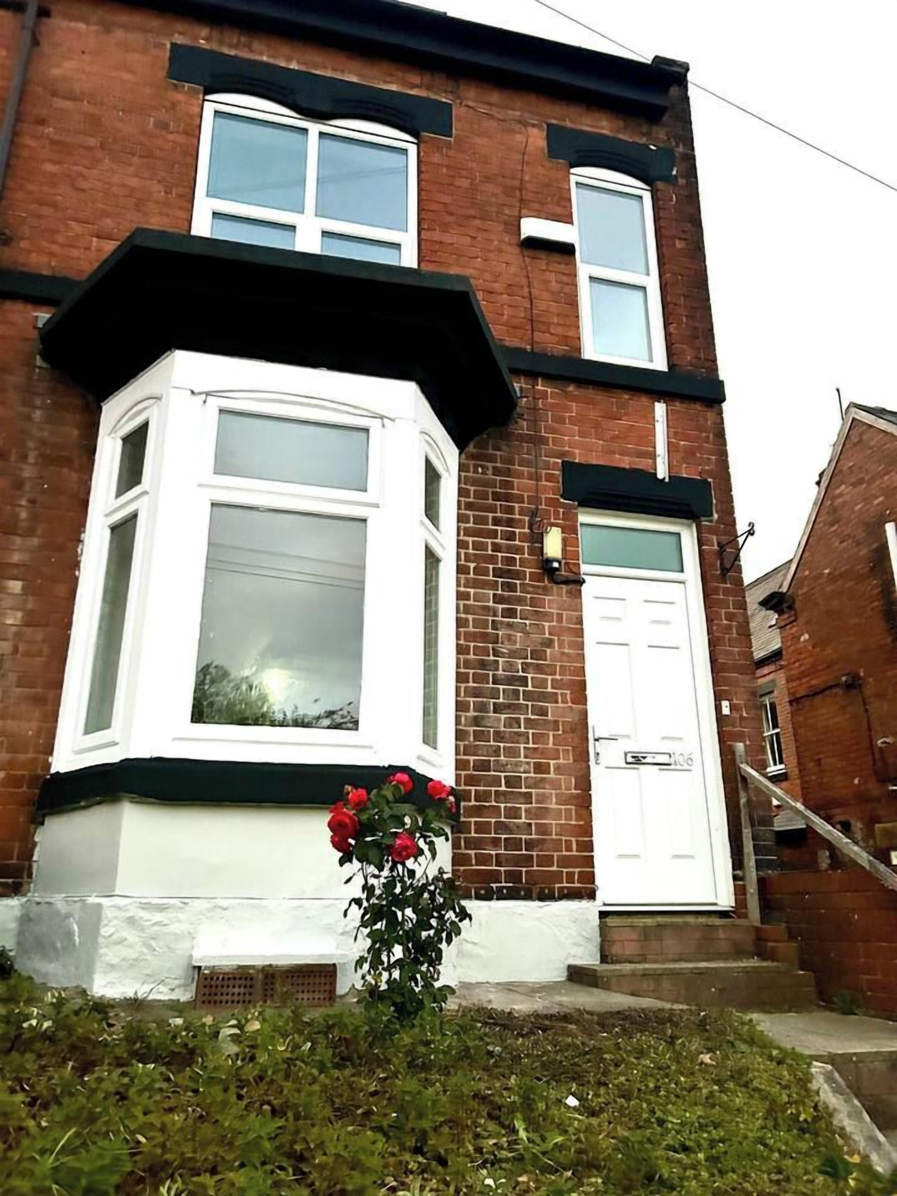 A two-story brick house with a bay window and a white door.