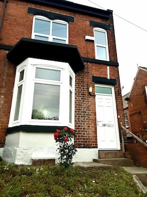 A two-story brick house with a bay window and a white door.