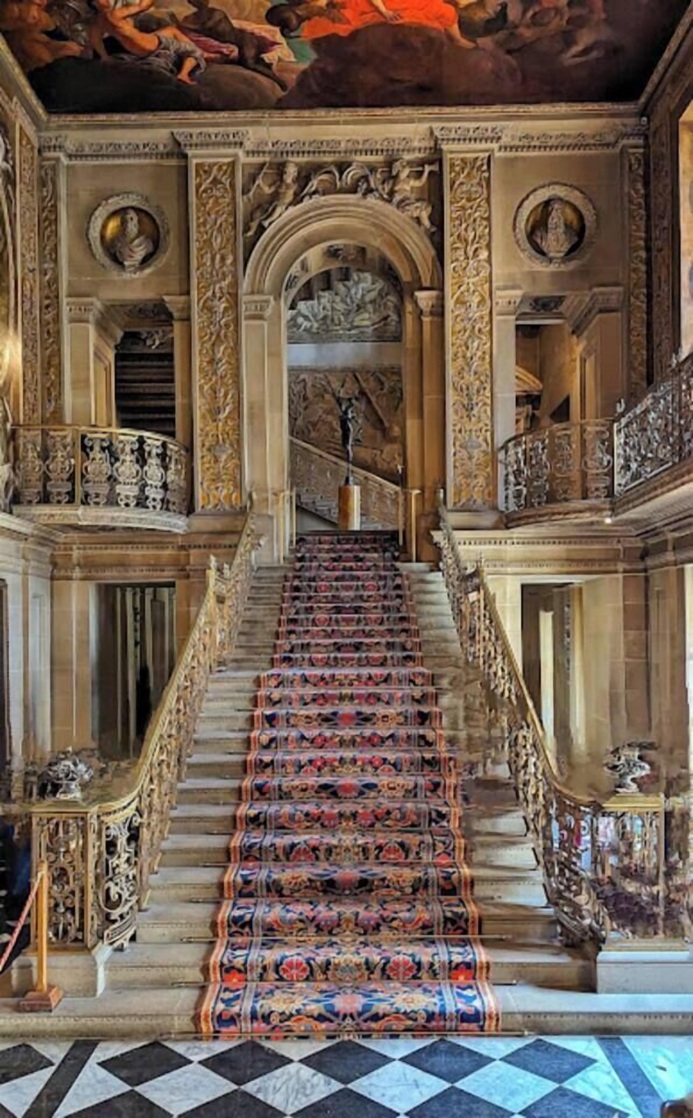 A grand staircase with ornate railings and a patterned carpet.