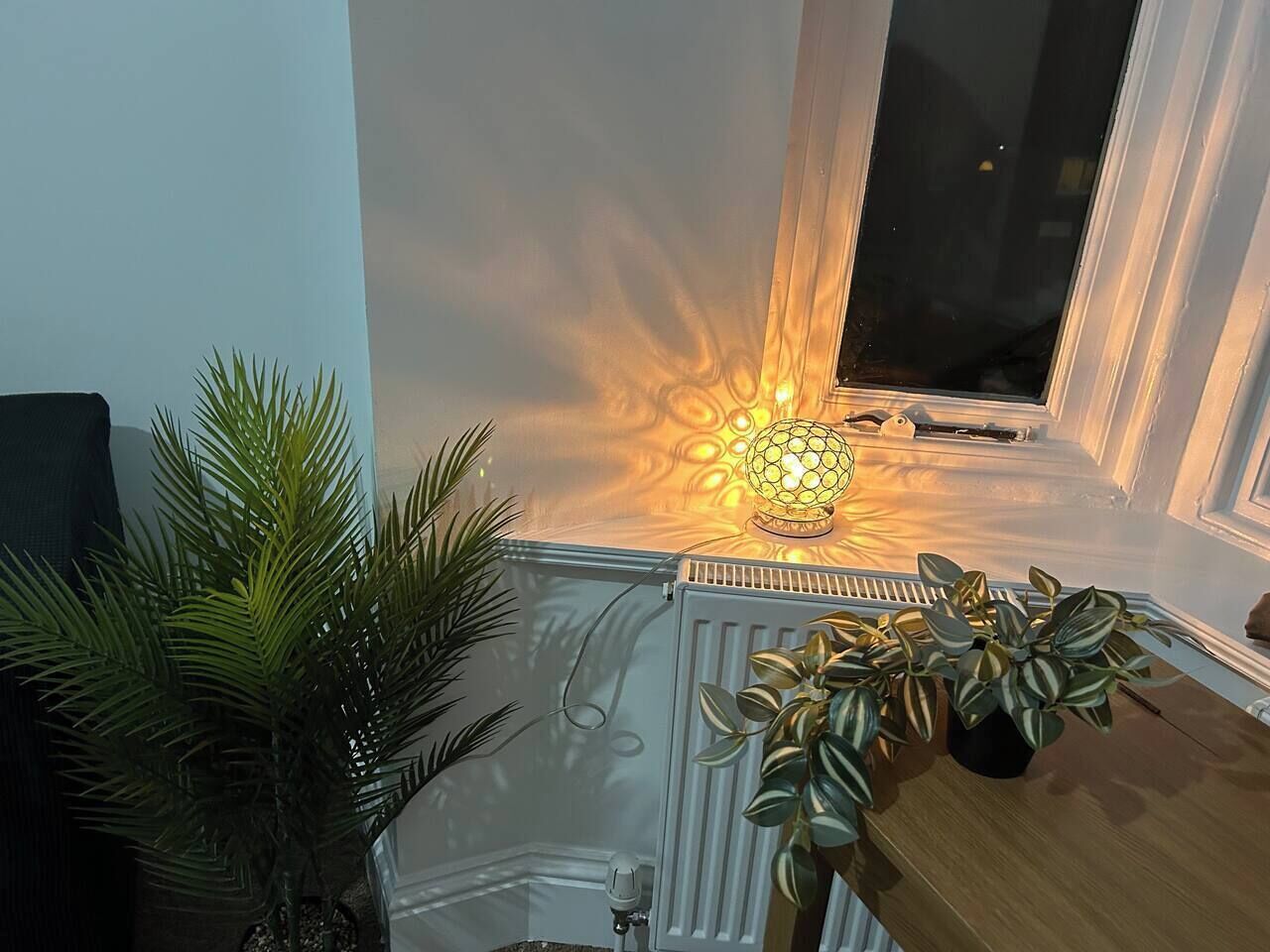 A room with a radiator, a window, and a decorative light fixture.