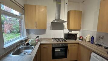 A compact kitchen with a sink, stove, microwave, and oven.