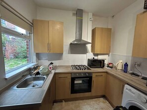 Een kleine keuken met een spoelbak, fornuis, magnetron en oven.