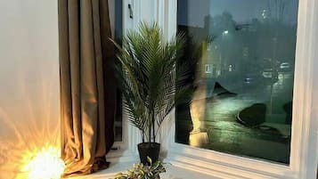 A room with a large window, a table, a chair, and a potted plant.