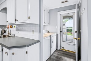 A kitchen with white cabinets, a stainless steel sink, and a window overlooking a driveway.