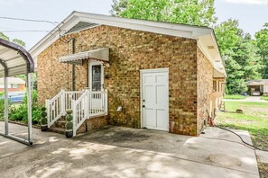 A small brick building with a white door, a covered porch, and a small staircase.