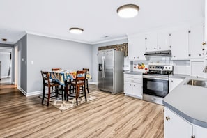 A modern kitchen with white cabinets, stainless steel appliances, and a dining area with a table and chairs.