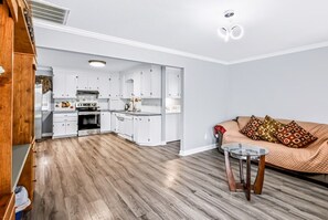 A modern kitchen with white cabinets, a central island, and a dining area with a glass table and chairs.
