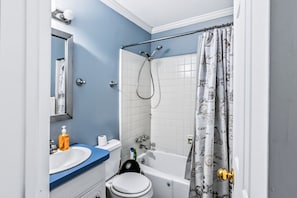 Un bagno con vasca, WC, lavandino e tenda da doccia decorata.
