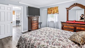 A bedroom with a bed, dresser, television, and a mirror. - Charming Single-Family Home (Greenville)