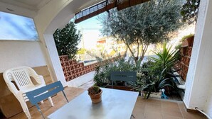 Eine Terrasse mit Tisch, Stühlen, einem Blumentopf und einer Bank.