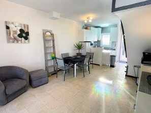Un espacio habitable pequeño con zona de comedor, kitchenette y sofá.