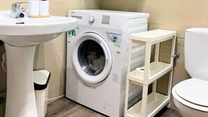 Ein kleines Badezimmer mit Waschmaschine, Waschbecken und Toilette.