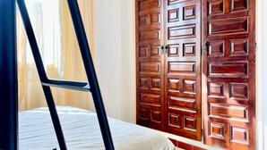 Ein Schlafzimmer mit einem Bett, einem Holzschrank und einem Fenster mit Vorhängen.